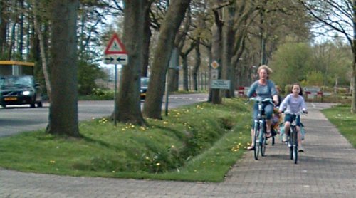 Mutter und Kind, radfahren auf ein Radweg. Einer Abstand von mehreren Metern zwischen Fahrbahn und Radweg.